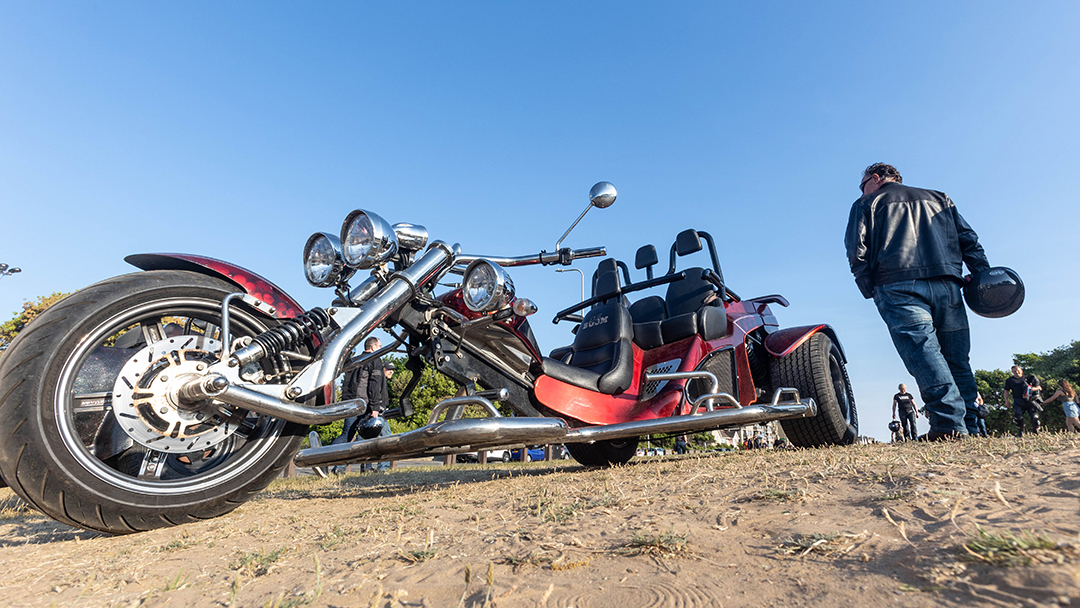 A motorbike rider walks past a motor trike